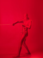 an anxious red man in a red leotard, dragging a heavy burden,