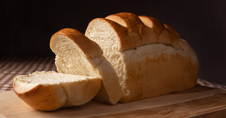 Breakfast table in Brazil, homemade bread on a brown and beige checkered tablecloth, dark background, selective focus.