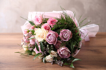 Beautiful bouquet with roses on wooden table