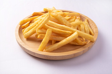 French fries placed on a round wooden plate, white background, selective focus.