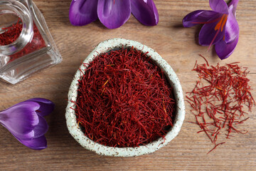 Dried saffron and crocus flowers on wooden table, flat lay