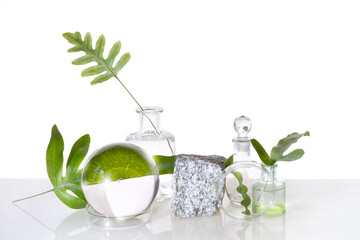 Natural Green laboratory. Abstract floral arrangement. Grey granite podium, space for your product. Reflections of leaves distorted in water. Exotic green leaves in transparent glass jars, tubes.