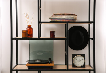 Stylish turntable with vinyl record on shelving unit indoors