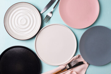 Some different empty plates with tableware on blue background - obrazy, fototapety, plakaty