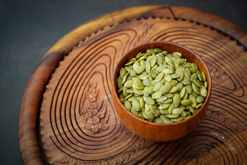 Top view of sunflower seeds in a wooden bowl on a wooden dark background.