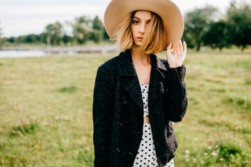 Elegant stylish blonde short hair girl in hat posing in the field