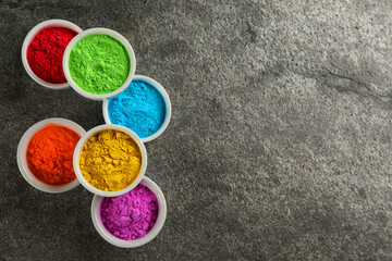 Colorful powder dyes on grey background, flat lay with space for text. Holi festival