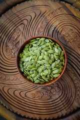 Top view of sunflower seeds in a wooden bowl on a wooden dark background.