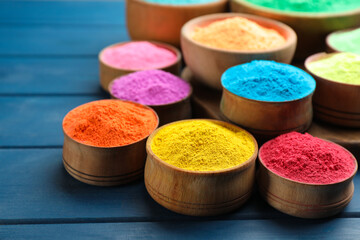 Colorful powder dyes on blue wooden background, closeup. Holi festival
