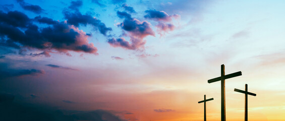 Easter concept. Cross of Jesus Christ empty over dramatic sunrise sky panorama with sclouds.