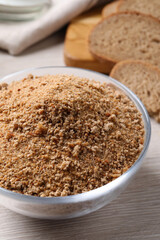 Fresh breadcrumbs in bowl on white wooden table
