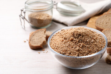 Fresh breadcrumbs in bowl on white wooden table. Space for text