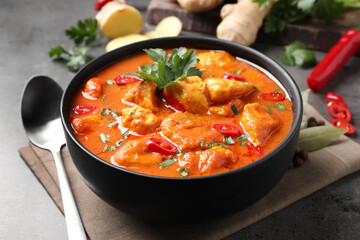 Bowl of delicious chicken curry on grey table