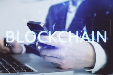 Double exposure of man's hands holding and using a phone and crypto currency blockchain theme...