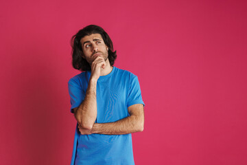 Puzzled brunette man in t-shirt think and looking upward