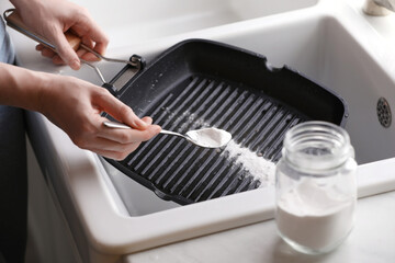 Woman using baking soda to grill pan indoors, closeup