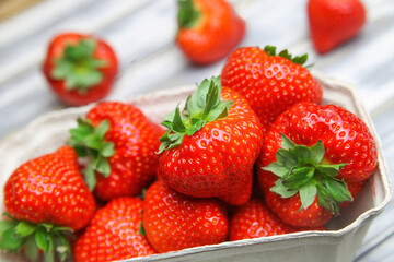 Closeup of isolated ripe fresh strawberries from german farmers market in cardboard box on white wood table
