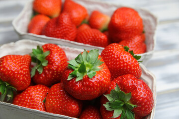 Closeup of isolated ripe fresh strawberries from german farmers market in cardboard box on white wood table