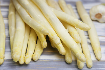 Closeup of isolated pile raw white uncooked asparagus spears on wood table