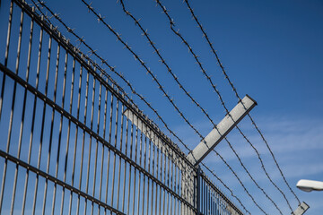 Fototapeta premium barbed wire fence too keep out burglars from home and keep in prisoners in imprisonment