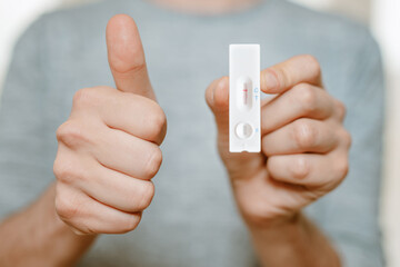 negative test result of a home use corona rapid test kit with thumb up shows not infected person is...