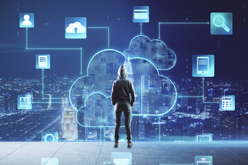 Cloud storage concept with person back in front of virtual screen with cloud application symbols on night megapolis city background