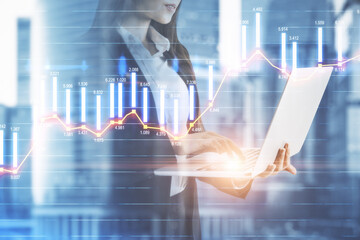 Businesswoman counting the trading bar charts and holding a laptop on the background with city view, market and analysis concept. Double exposure
