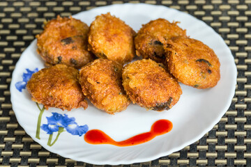 Homemade deep-fried vegetable cutlet served with red tomato sauce.