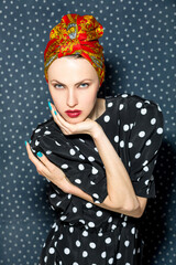 portrait of a woman in head scarf and polka dots dress over polka dots dark background