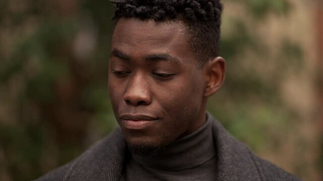 Handsome young black man standing outdoors thinking