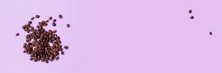 Roasted brown coffee beans randomly scattered on a purple background. Banner. Flat lay, top view