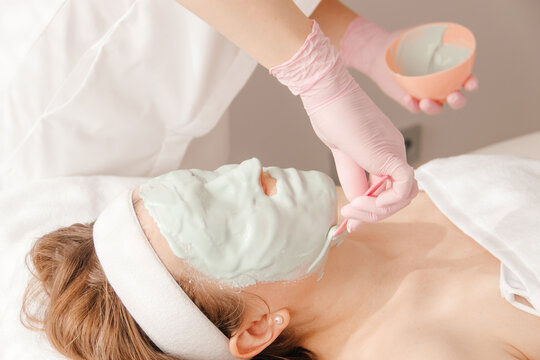 cosmetologist applies an alginate mask to a girl
