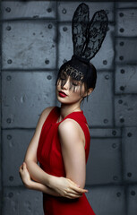 Young woman in black rabbit or hare fancy mask and red dress.