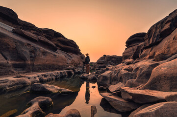 Woman explorer standing in large rocky rapids in the evening at Hat Chom Dao