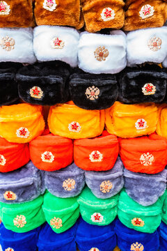 Rows of russian winter hats of different colors with army emblems at the street market at Old Arbat street in Moscow, iconic popular souvenir from Russia. High quality photo