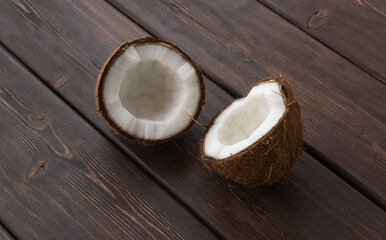 split coconut on wooden planks. Coco, ripe palm fruit. outside of the fruit is covered with a...
