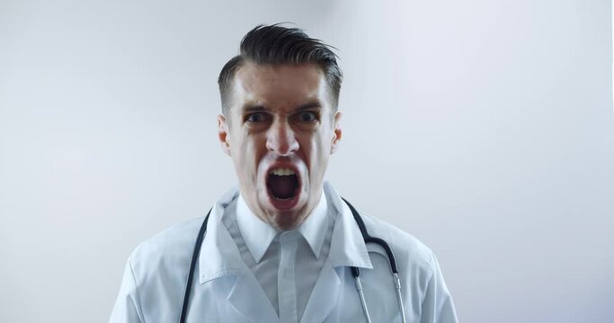 Close-up of angry doctor scolding and shouting at employees threatening with a finger and shouting aggressively at the camera.