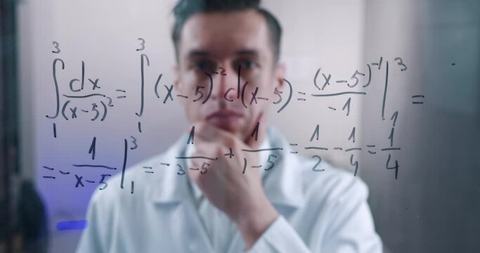 Man Scientist thinks over the solution of the integral equation, drawn on a glass board in a laboratory. The mathematician solves the problem.