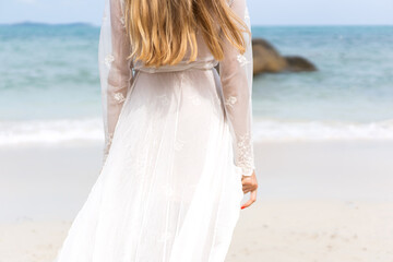 Fototapeta na wymiar beautiful girl in a white dress walks along the beach