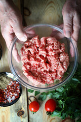 Minced meat in a bowl and the hands of the cook. Cooking minced meat for burgers or grilling.