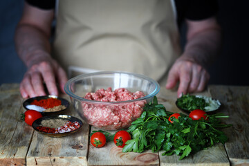Minced meat in a bowl and the hands of the cook. Cooking minced meat for burgers or grilling.