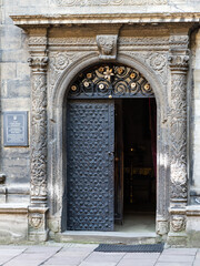 LVIV, UKRAINE - April, 2021: The door and Ancient columns with Renaissance bas-reliefs and plants patterns in the wall of Chapel of the three saints 16th century.