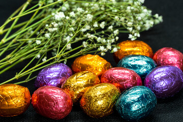 Obraz na płótnie Canvas chocolate easter eggs and dried flowers on black background