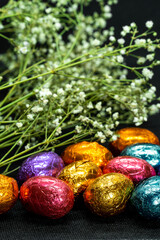 chocolate easter eggs and dried flowers on black background