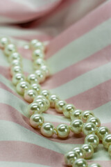 pearl necklace on soft pink satin white striped fabric