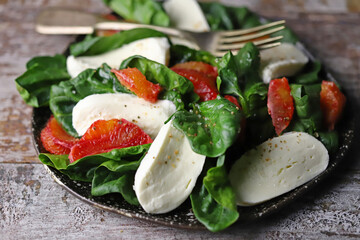 A la caprese salad with spinach, mozzarella and orange. Healthy food. Diet concept. Beautiful and delicious salads.