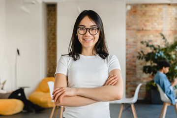 Successful young asian businesswoman with arms crossed in office