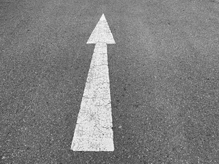 Abstract black and white tone of asphalt street texture with white painted arrow sign and symbol.