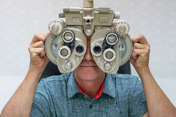 Male checks his vision on the machine checking patient vision at eye clinic or optics store