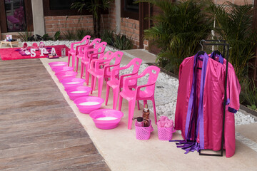 Plastic chairs with punch bowls arranged to do foot treatments for girls; spa theme children's party.